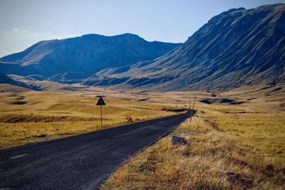 Road leading towards mountains against sky