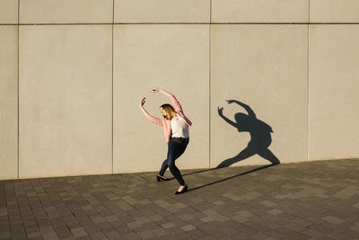 Full length of woman standing against wall