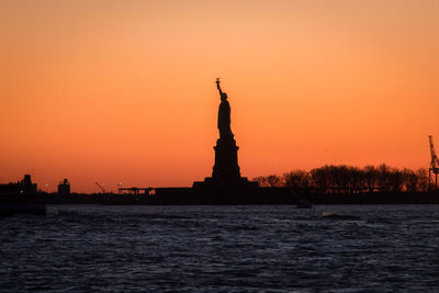 Low angle view of silhouette statue of liberty against sky during sunset