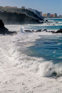 Waves splashing on shore against sky