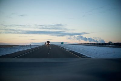 Road by sea against sky during sunset