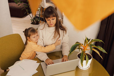 Working mom works from home office with kid. woman using laptop. child drawing. woman freelancer