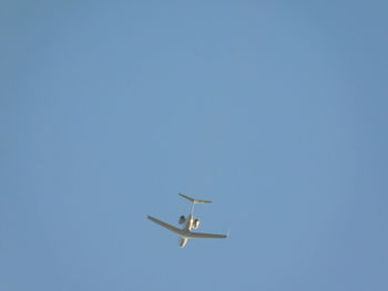 Low angle view of airplane flying against clear blue sky