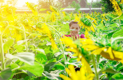 Portrait of smiling woman standing amidst flowers