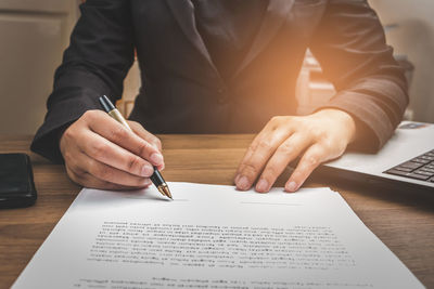 Midsection of man holding paper with text on table