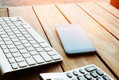 High angle view of smart phone by computer keyboard on table