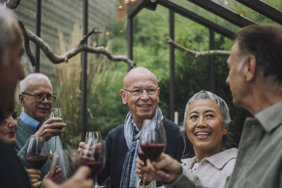 Smiling senior man talking to retired male and female friends at party