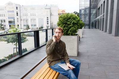 Man talking on the phone holding a laptop in his hand in the yard