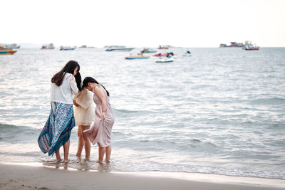 Female friends standing on shore at beach