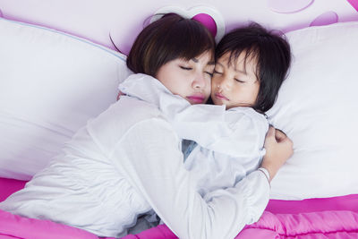 Young mother with daughter sleeping on bed at home