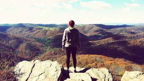 Rear view of man standing on mountain against sky