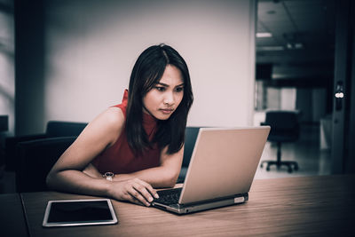 Portrait of woman using phone while sitting on table