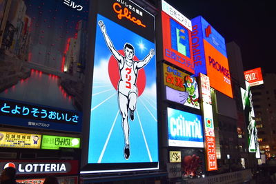 Low angle view of illuminated sign against buildings in city