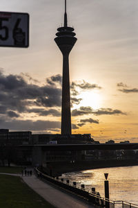 Silhouette of tower against cloudy sky during sunset