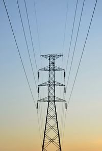 Low angle view of electricity pylon against sky during sunset