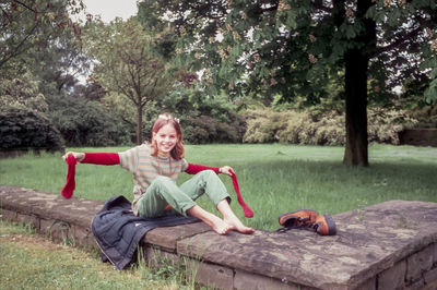 Portrait of smiling young woman sitting on tree