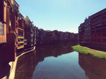 Canal amidst buildings against sky in city