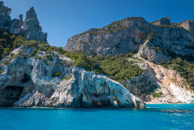 Rock formations by sea against blue sky