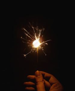 Person hand holding firework display at night