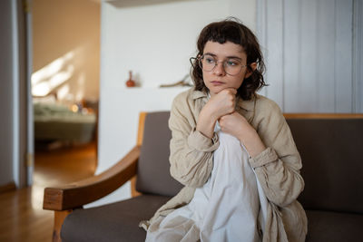 Portrait of young woman sitting on sofa at home