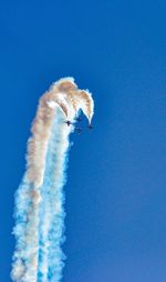 Low angle view of airplane flying against clear blue sky