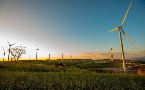 Windmill on field against sky during sunset