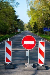 Arrow sign on road against sky