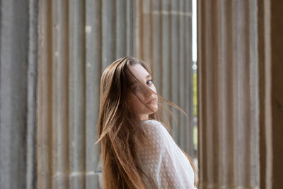 Portrait of young woman standing against columns