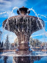 Low angle view of fountain against blue sky