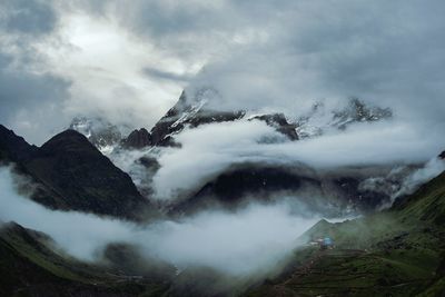 Scenic view of kedarnath temple sorrounding mountains covered with clouds and snow, india