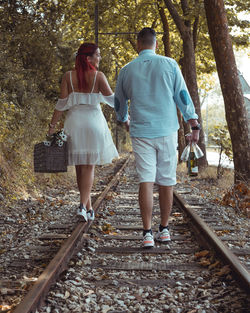 Rear view of people walking on railroad tracks