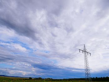 Low angle view of electricity pylon on field against sky