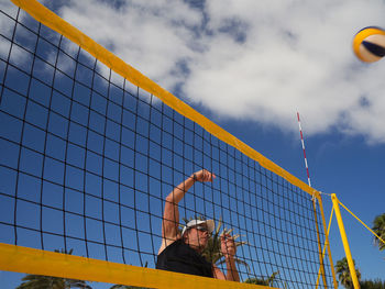 Man playing volleyball at beach against sky