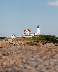 Lighthouse by sea against clear sky