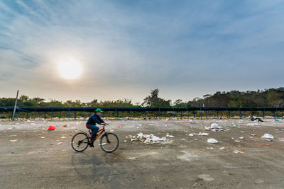 Man cycling by garbage at parking lot