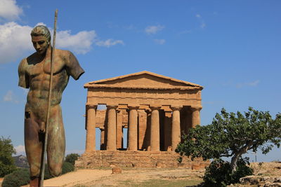 Statue by historic building against sky