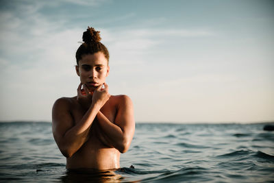 Portrait of shirtless young woman swimming in sea against sky