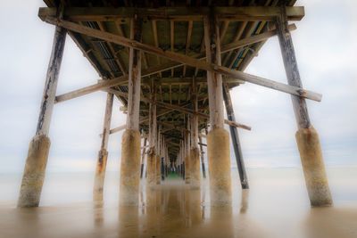 Low angle view of pier over sea against sky
