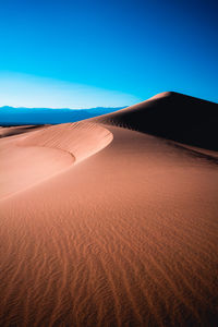 Sand dunes in desert against clear blue sky