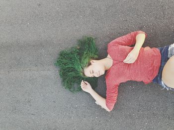 Woman with dyed hair lying down on road