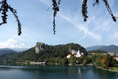 Scenic view of tree mountain by lake bled against sky