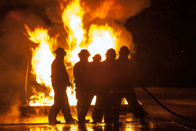 People standing against fire at night