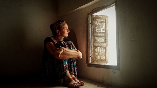 Young woman with arms crossed looking through window