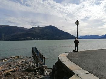 Rear view of man standing by sea against sky