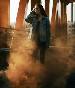 Young woman standing on footbridge during sunset