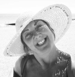 Portrait of cheerful woman wearing hat while standing at beach