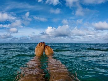 Low section of woman in sea against sky