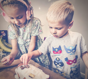 Close-up of cute kids decorating a cake