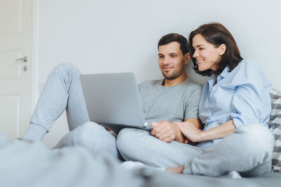 Low angle view of couple watching video over laptop on bed at home