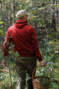 Midsection of man standing by tree in forest